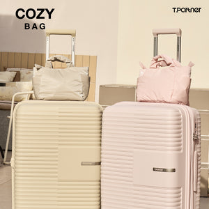 กระเป๋าสะพายไซส์มินิ Cozy Bag สีเบจและสีชมพูอ่อน วางคู่กับกระเป๋าเดินทาง